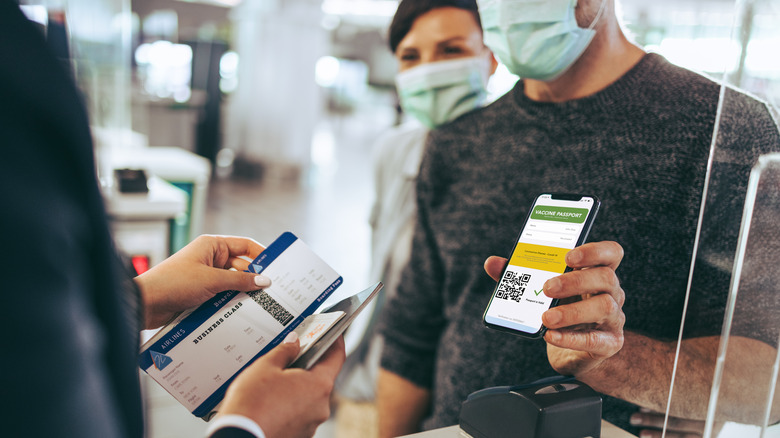 Traveler shows health passport of vaccination certification on phone at airport, to certicy that have been vaccinated of coronavirus covid-19