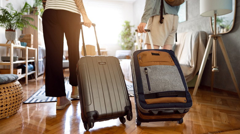couple with suitcase entering home